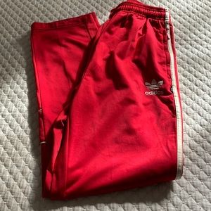 Adidas track pants with crème colored stripes and logos.